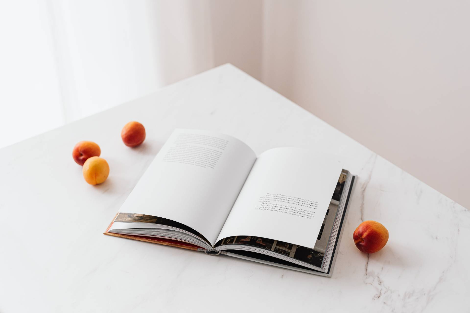 Open book on a marble table surrounded by apricots