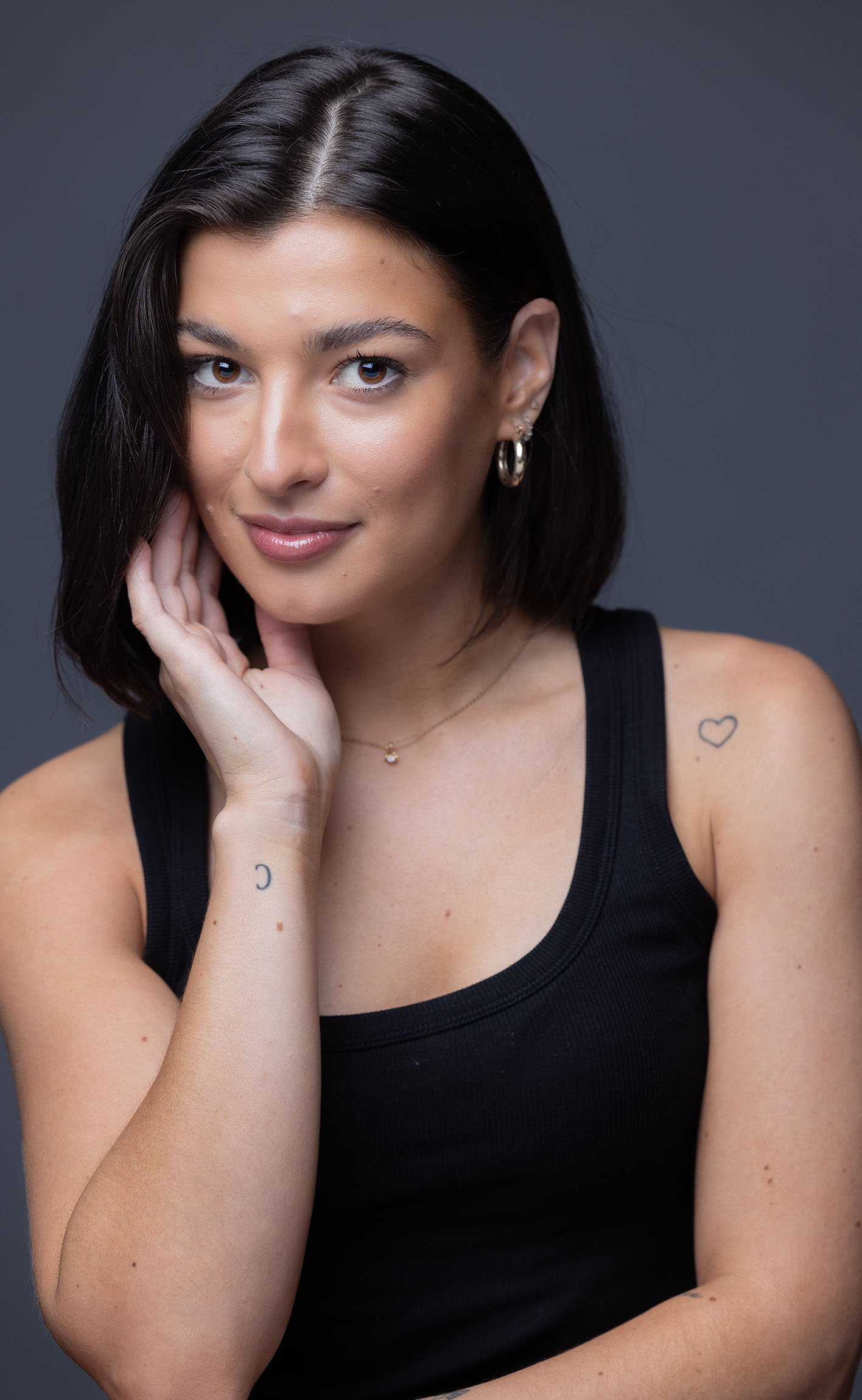 Theatrical and commercial actor headshot of Bella in a black tank top against a gray studio backdrop, Ashland Oregon