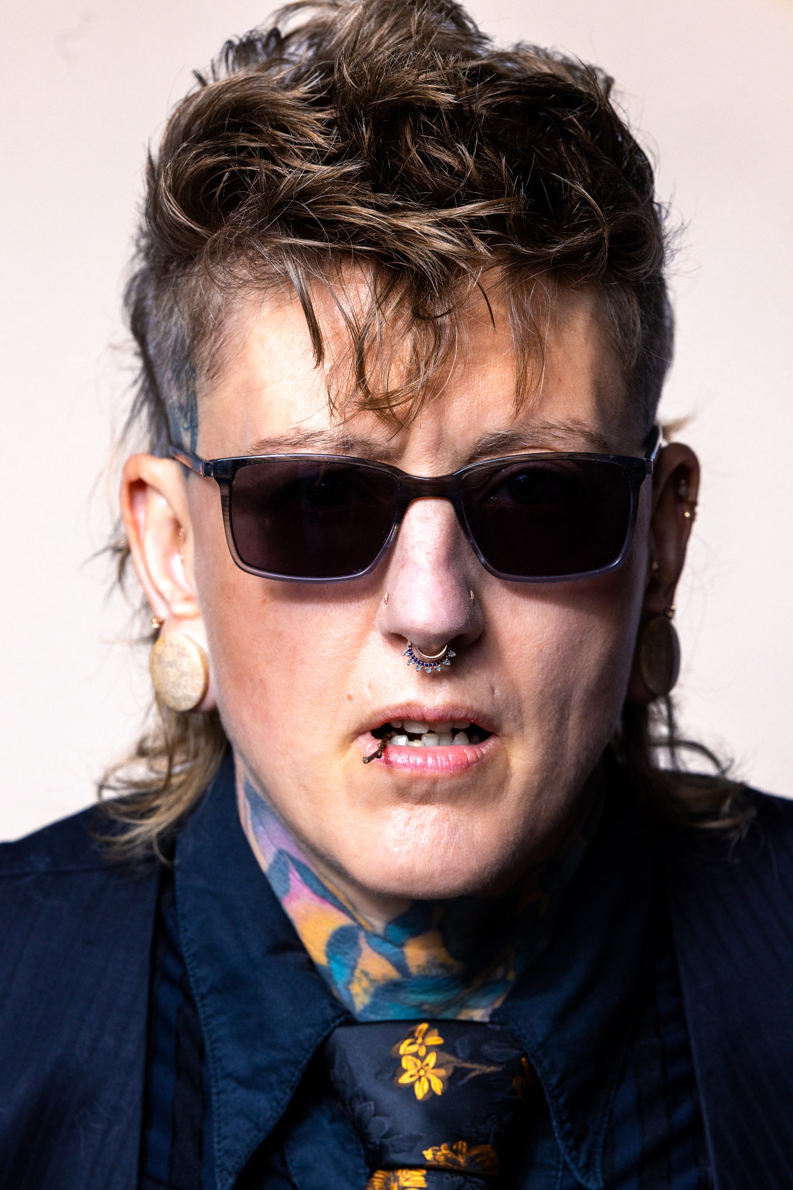 Close-up portrait of Chari in sunglasses with visible tattoo artwork